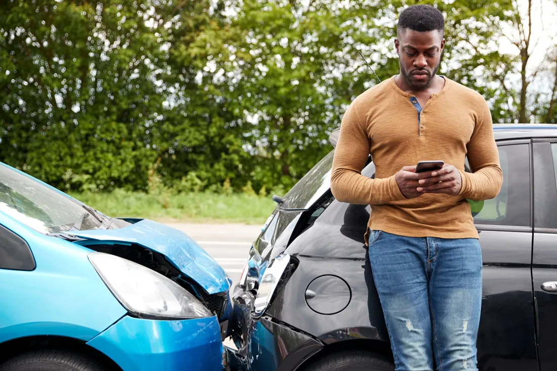Motorist at the roadside after an accident phoning a reliable car recovery service